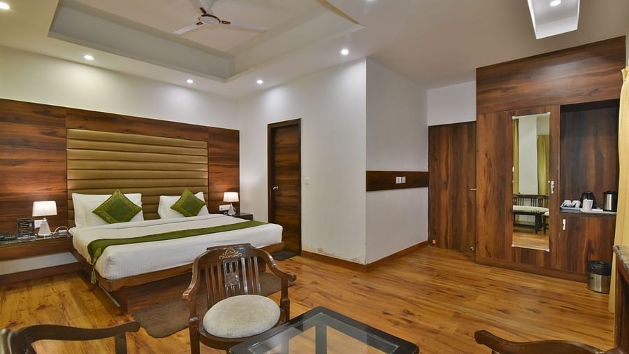 A large bed placed in front of two sofas at the Luxury Room Without Balcony at DLS Highland Resort and Spa, Mussoorie.